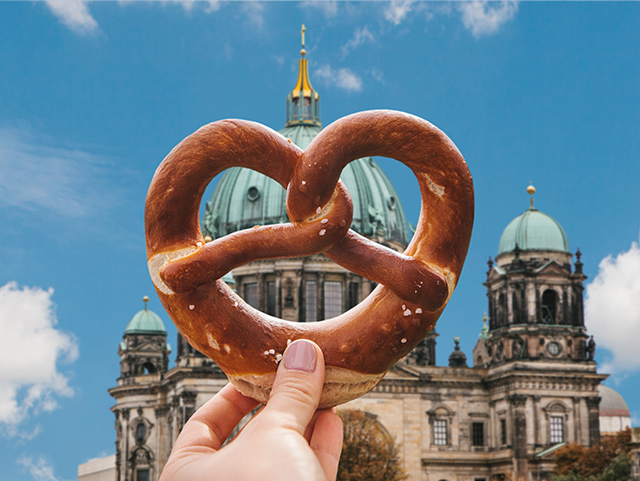 Girl Holding A Brezel In Front Of The Reichstag + Blue Clear Sky